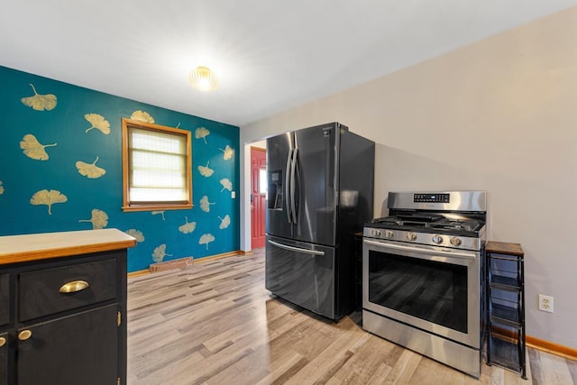 kitchen featuring black fridge with ice dispenser, light wood-type flooring, gas stove, dark cabinetry, and baseboards