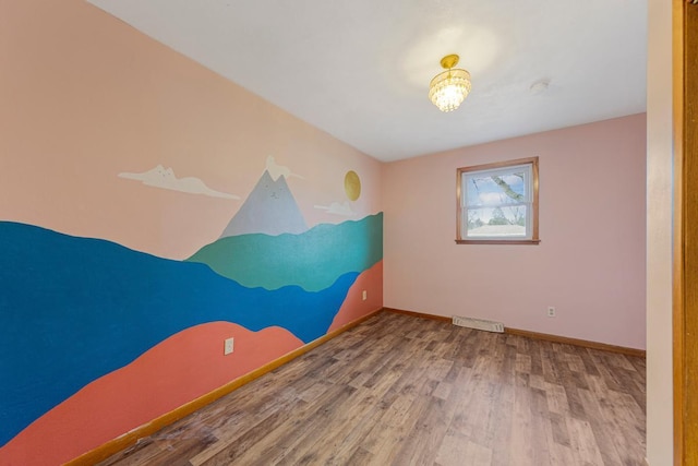 unfurnished room with baseboards, visible vents, and wood finished floors