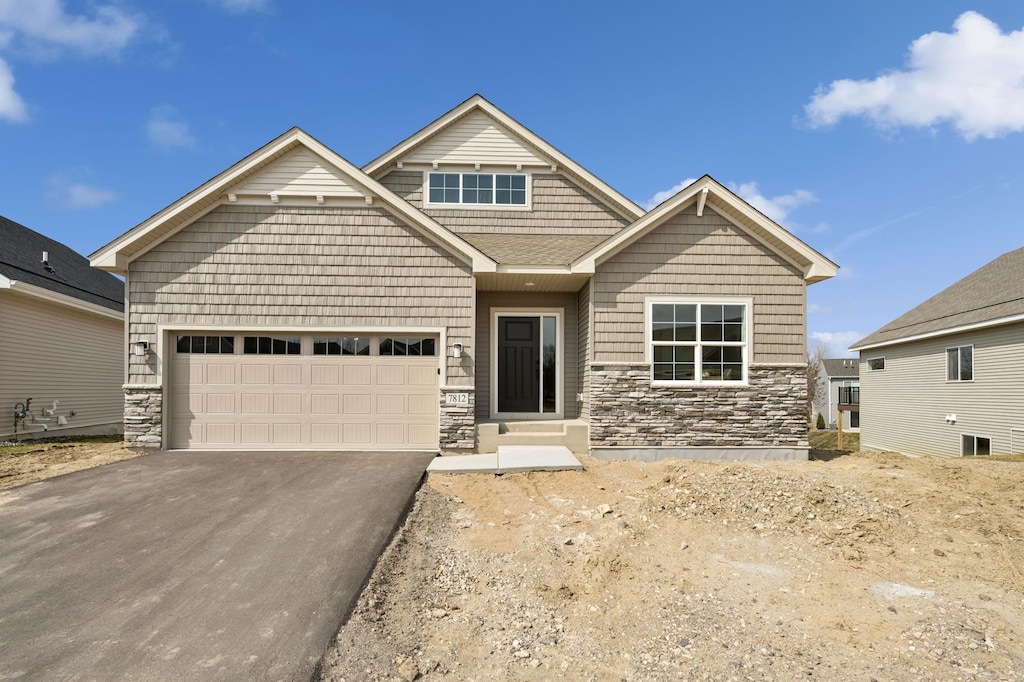 craftsman house featuring an attached garage, driveway, stone siding, and central AC unit