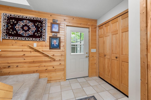 entryway with wood walls and light tile patterned flooring
