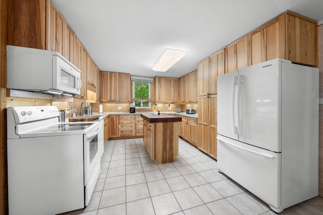 kitchen featuring a sink, decorative backsplash, white appliances, a kitchen island, and light tile patterned floors