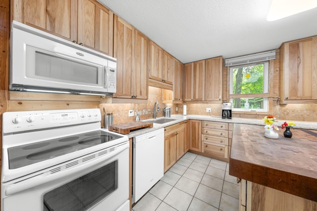 kitchen with light tile patterned floors, a sink, white appliances, decorative backsplash, and a textured ceiling
