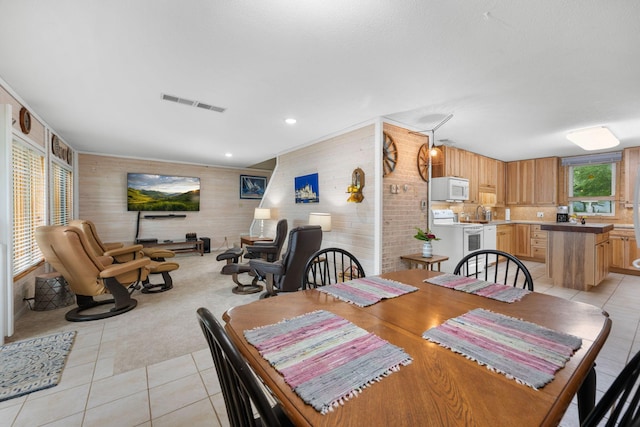 dining area featuring wood walls, visible vents, and light tile patterned floors