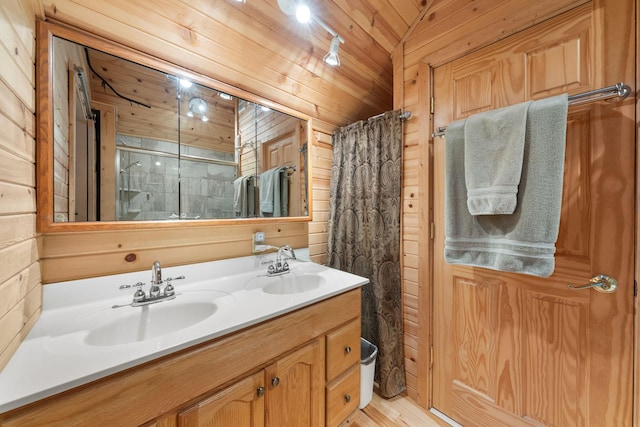 full bathroom with wooden walls, a sink, a shower with shower curtain, and double vanity