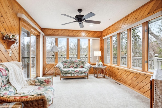 sunroom / solarium featuring wood walls, a healthy amount of sunlight, and carpet flooring
