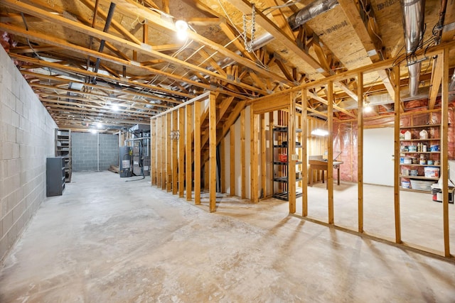 unfinished below grade area featuring water heater and concrete block wall