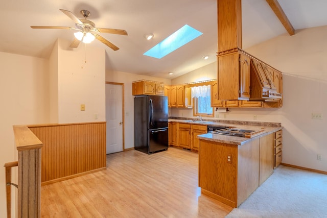 kitchen with freestanding refrigerator, a peninsula, dishwashing machine, lofted ceiling with skylight, and a ceiling fan