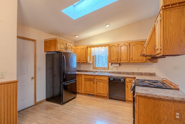 kitchen with lofted ceiling with skylight, light countertops, a sink, light wood-style flooring, and black appliances