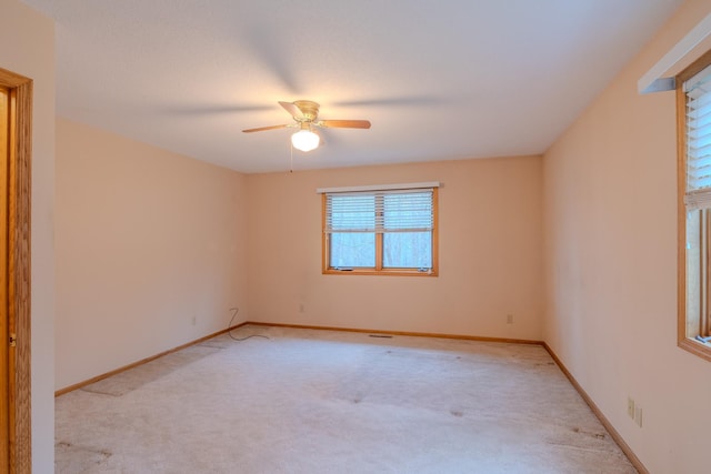 empty room with baseboards, a ceiling fan, and light carpet