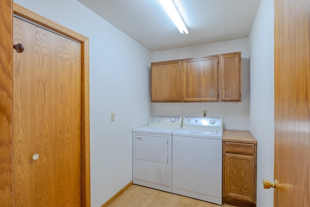 washroom featuring light wood-style floors, baseboards, cabinet space, and washing machine and clothes dryer