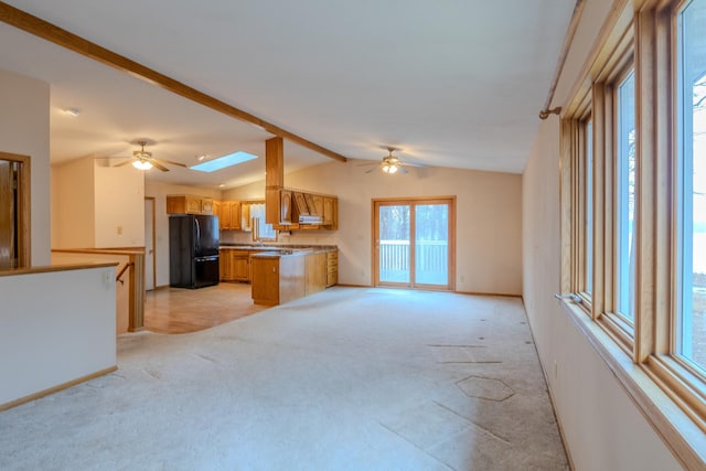 unfurnished living room with light colored carpet, a ceiling fan, baseboards, and lofted ceiling with skylight