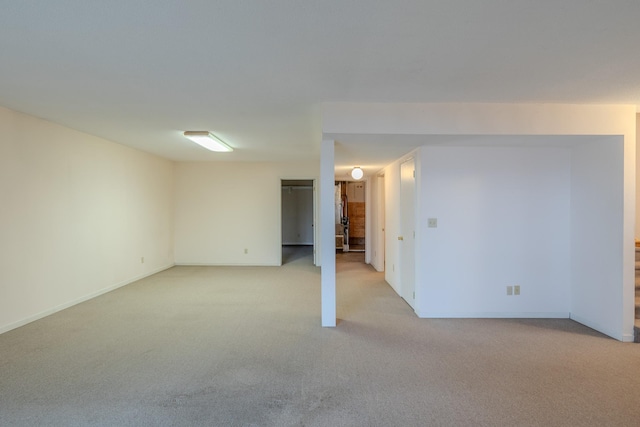 finished below grade area featuring baseboards and light carpet