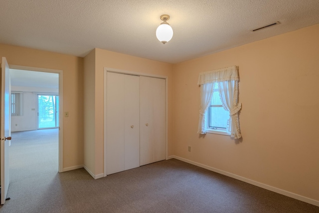 unfurnished bedroom featuring visible vents, carpet floors, a closet, baseboards, and a textured ceiling