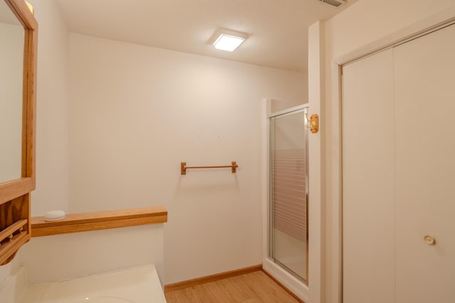 bathroom featuring baseboards, a stall shower, wood finished floors, and visible vents