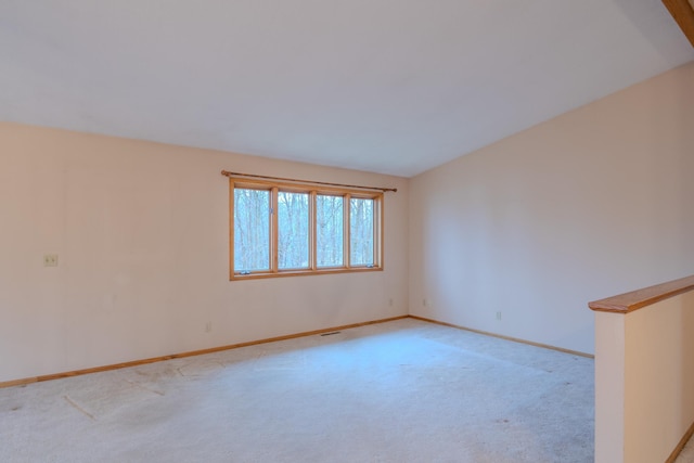 spare room with baseboards and light carpet