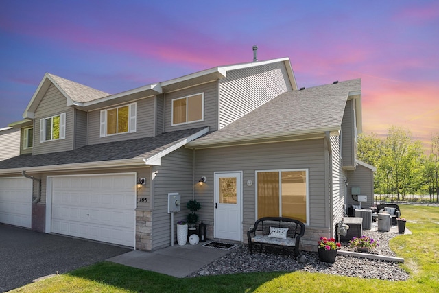 3831 232nd Ave NW Unit 105, Saint Francis, MN 55070 - view of front of home featuring central air condition unit, an attached garage, a shingled roof, and asphalt driveway