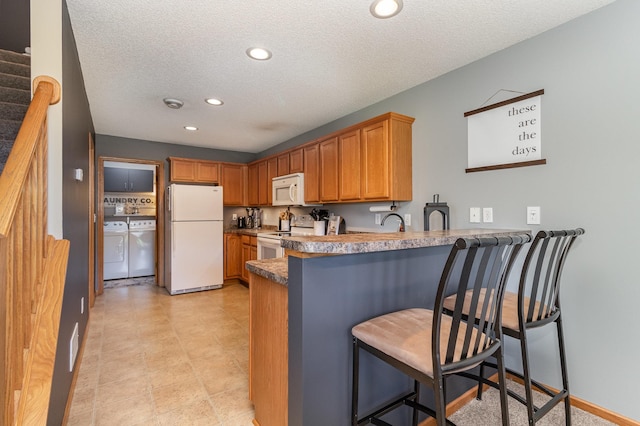 3831 232nd Ave NW Unit 105, Saint Francis, MN 55070 - kitchen with white appliances, washer and clothes dryer, a peninsula, recessed lighting, and a textured ceiling