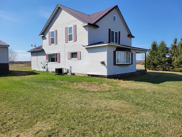 rear view of property with a yard, central AC, and metal roof