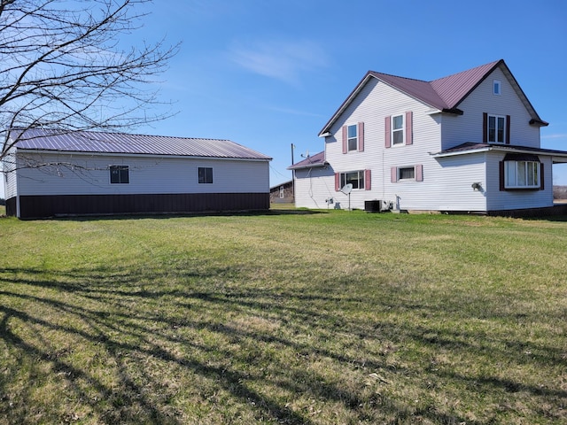 back of property featuring a yard, central AC, and metal roof
