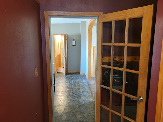 hallway with stone tile floors and baseboards