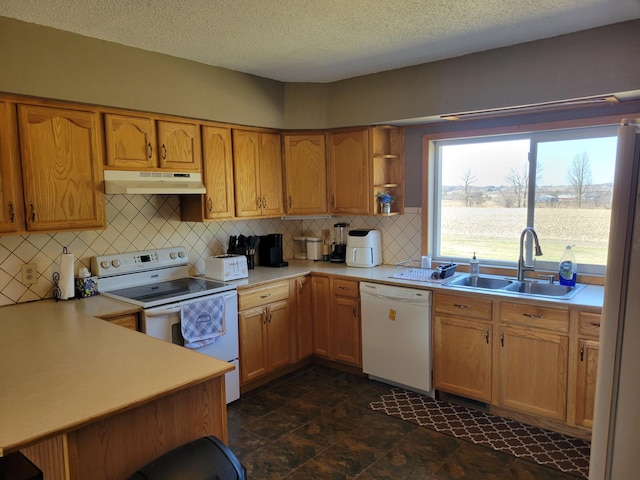 kitchen featuring a sink, white appliances, light countertops, backsplash, and under cabinet range hood