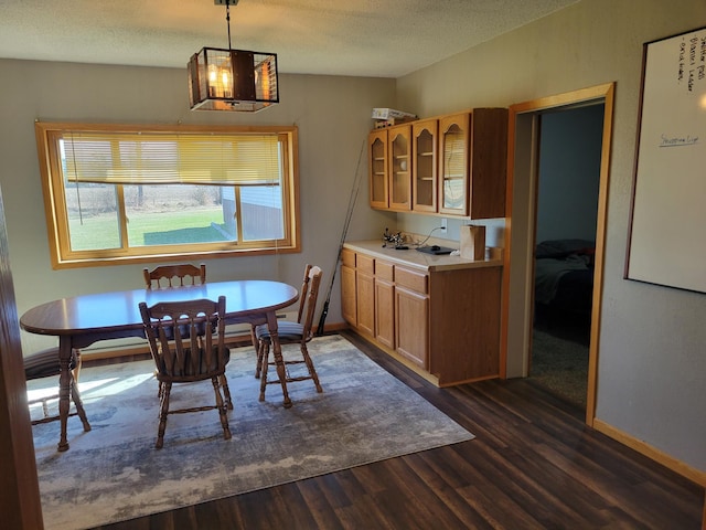 kitchen featuring brown cabinets, light countertops, glass insert cabinets, a textured ceiling, and dark wood-style flooring