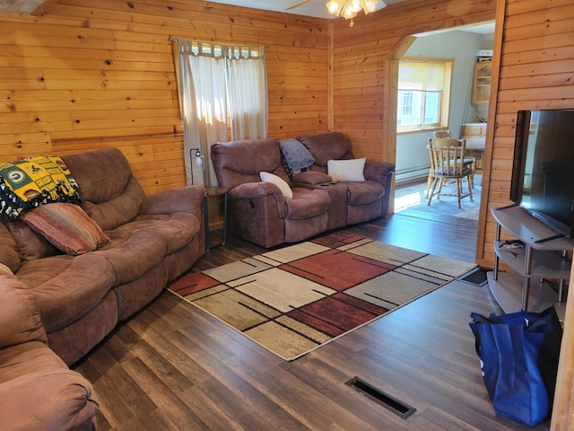 living room featuring a baseboard heating unit, visible vents, wood walls, wood finished floors, and ceiling fan