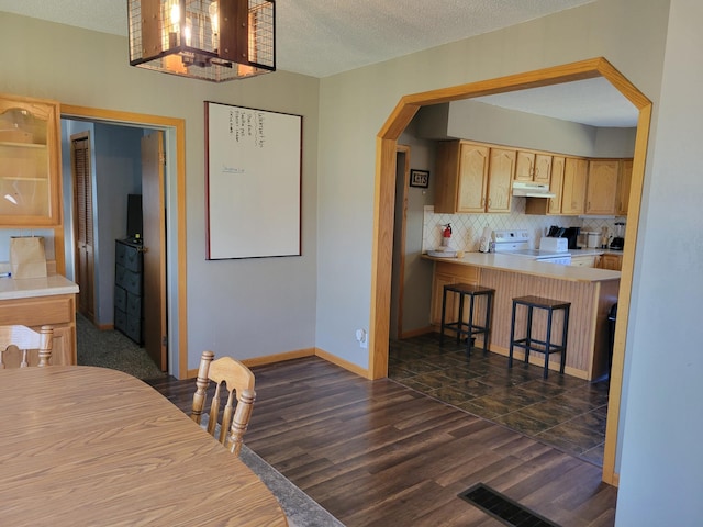 dining space with arched walkways, a textured ceiling, dark wood-style flooring, visible vents, and baseboards