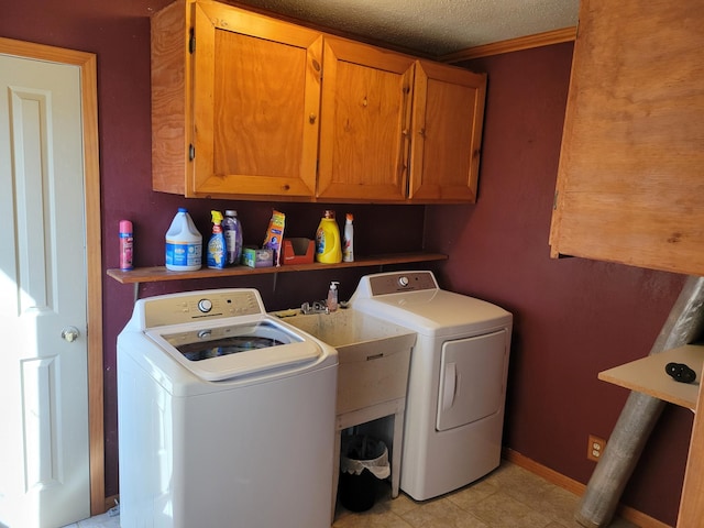 clothes washing area featuring cabinet space, a textured ceiling, washer and dryer, and light tile patterned floors