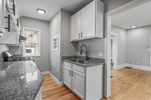 1527 Minnehaha Ave W, Saint Paul, MN 55104 - kitchen featuring dark stone counters, light wood-style floors, gas stove, white cabinetry, and a sink