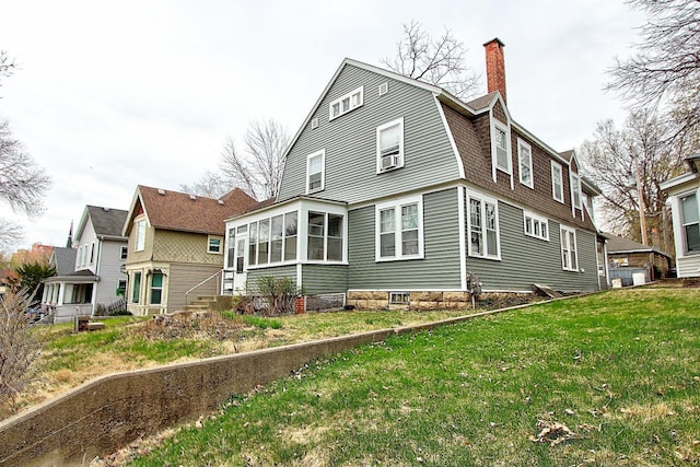 717 3rd St, Red Wing, MN 55066 - rear view of house with a sunroom, a lawn, a gambrel roof, and a chimney