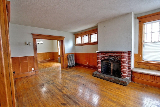 717 3rd St, Red Wing, MN 55066 - unfurnished living room with radiator, a wainscoted wall, wood-type flooring, and a textured ceiling