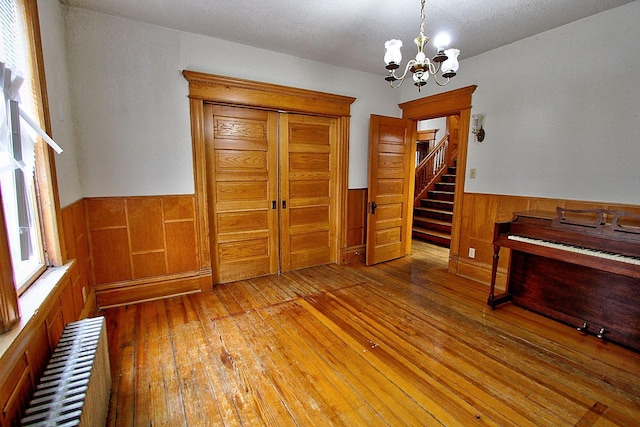 717 3rd St, Red Wing, MN 55066 - interior space featuring light wood finished floors, a wainscoted wall, an inviting chandelier, wood walls, and stairs