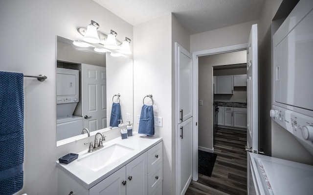 bathroom featuring stacked washer and dryer, wood finished floors, vanity, and baseboards
