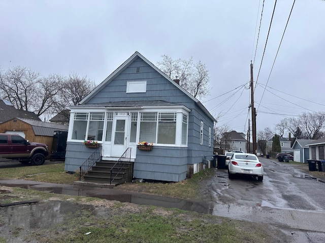 bungalow featuring roof with shingles, entry steps, and driveway