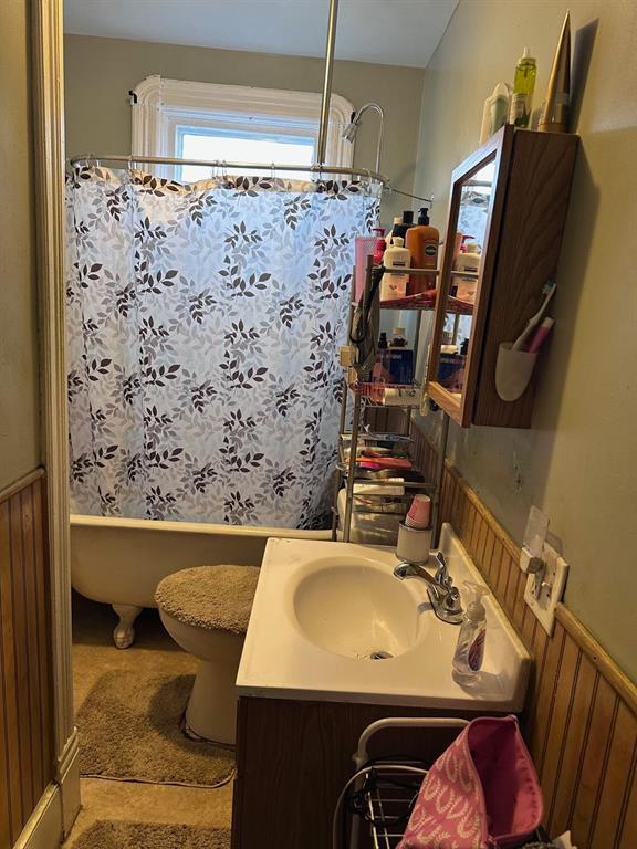 bathroom featuring shower / bath combo with shower curtain, toilet, wainscoting, and vanity