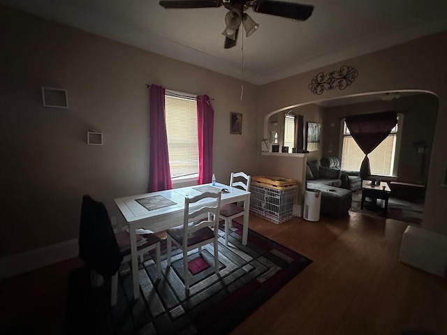 dining room featuring arched walkways, a ceiling fan, and wood finished floors