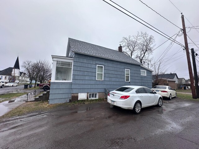 view of side of home featuring roof with shingles and a chimney