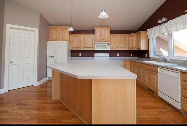 kitchen featuring lofted ceiling, light wood finished floors, light brown cabinets, and white appliances