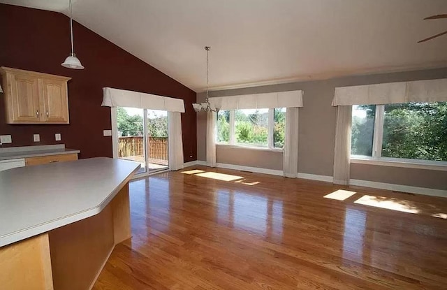 unfurnished dining area featuring a chandelier, high vaulted ceiling, light wood finished floors, and baseboards