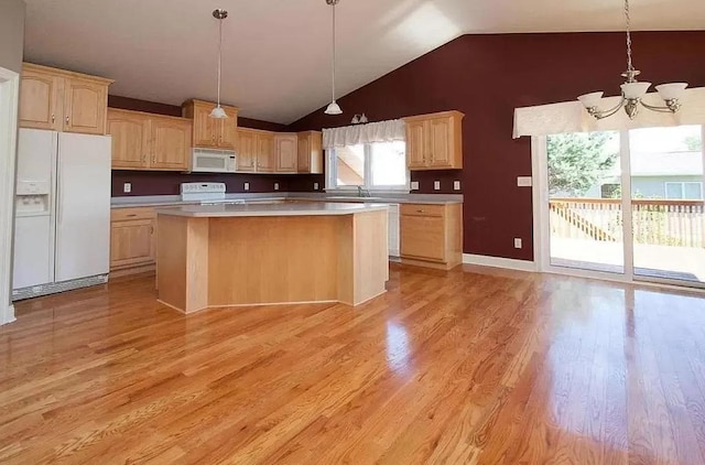 kitchen with vaulted ceiling, light brown cabinetry, white appliances, a notable chandelier, and a kitchen island