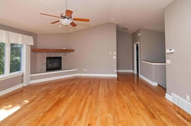unfurnished living room featuring light wood-type flooring, visible vents, lofted ceiling, a ceiling fan, and a fireplace