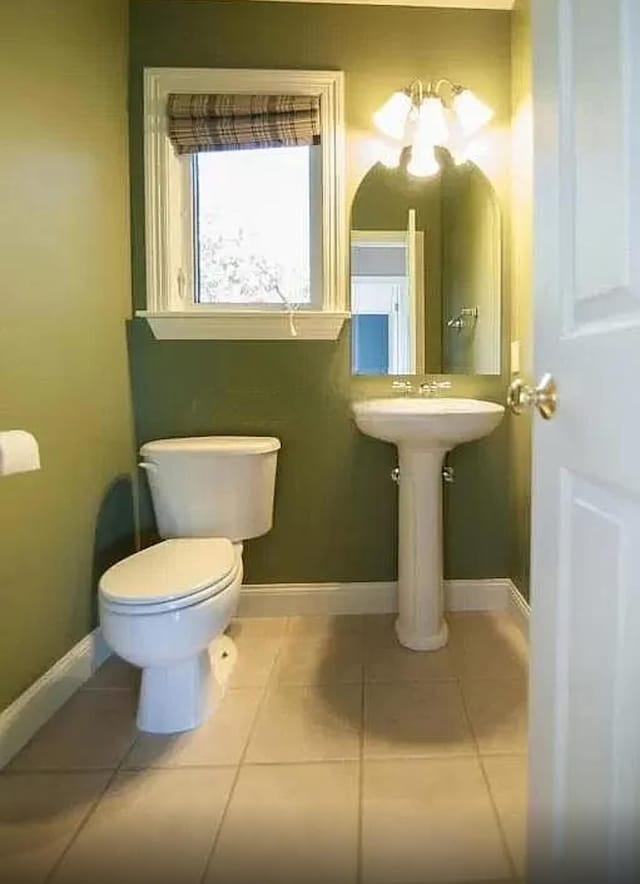 half bathroom with toilet, tile patterned floors, and baseboards
