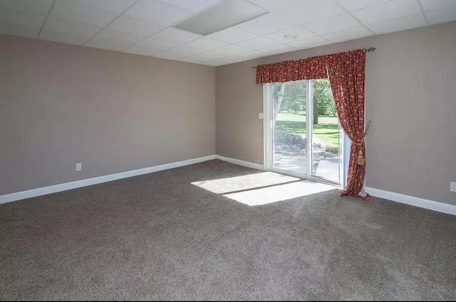 carpeted empty room featuring baseboards and a drop ceiling
