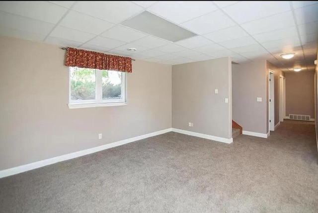 empty room with carpet floors, visible vents, baseboards, and a paneled ceiling