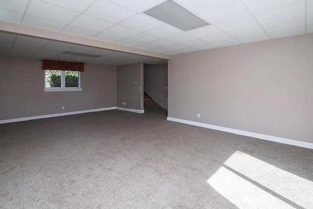 unfurnished room featuring carpet flooring, baseboards, and a drop ceiling