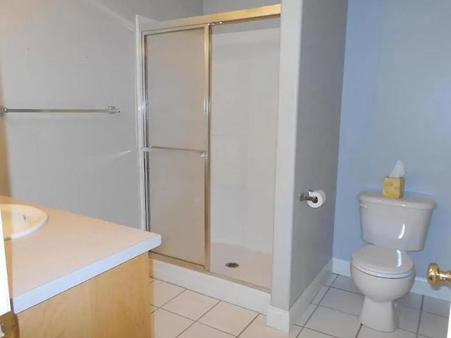 bathroom featuring toilet, a stall shower, vanity, baseboards, and tile patterned flooring