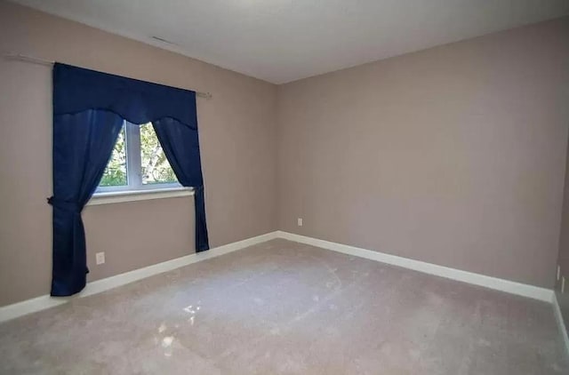 spare room featuring baseboards and carpet