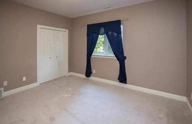 unfurnished bedroom with baseboards, carpet flooring, and a closet