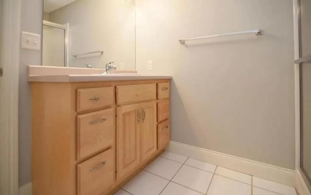 bathroom with a shower stall, baseboards, vanity, and tile patterned floors